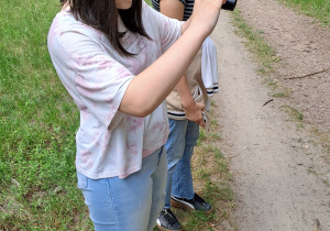 Uczennica wykonuje zdjęcie drogi aparatem fotograficznym.
