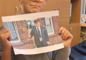 Dziewczynka prezentuje zdjęcie kolejarza w mundurze.
