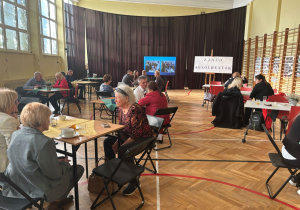 Rozmowy absolwentów i nauczycieli na sali gimnastycznej.