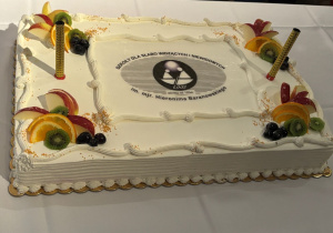 Śmietankowy tort z wykonanym z czekolady logo Ośrodka.