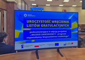 Monitor z napisem: Uroczystość wręczenia listów gratulacyjnych podsumowujących II edycję projektu „Młodzi zawodowcy” - programu stypendialnego Województwa Łódzkiego.