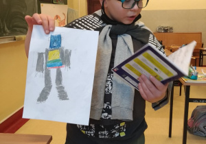 Uczeń czytający z zeszytu o swoim narysowanym robocie