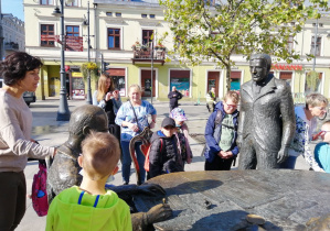 Dzieci stojące przed pomnikiem Trzech Fabrykantów.
