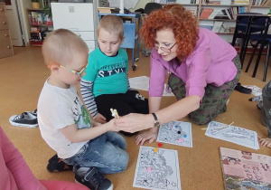Dzieci po okiem nauczycielki uczą posługiwać się pałeczkami.