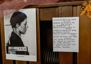 Czarno białe zdjęcie dziecka, obok wiersz napisane przez dziecko z obozu - wystawa okolicznościowa.