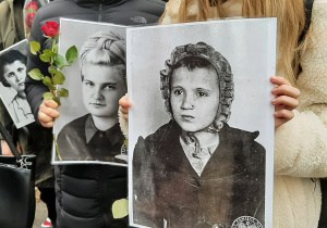 Uczniowie trzymający czarno-białe zdjęcia dzieci z czasów wojny.