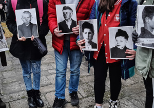Uczniowie trzymający w rękach 6 czarno-białych zdjęć dzieci z obozu na ul. Przemysłowej.