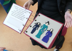 Nauczycielka prezentuje książkę o Kopciuszku, która oprócz powiększonego tekstu ma również napisy w brajlu i piękne wypukłe „ilustracje”.