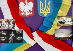 Praca wykonana z różnych materiałów: na fioletowy tle w centrum godło Polski i Ukrainy, na górze dwie dłonie w uścisku, bo bokach flagi w barwach narodowych, na dole napis: Solidarni z Ukrainą.