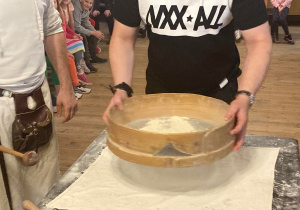 Uczeń przesiewa mąkę na pierniki.