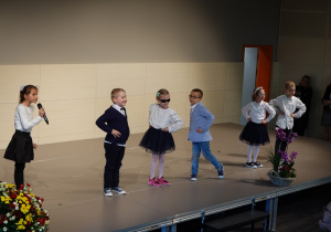 Uczniowie klas młodszych śpiewają na scenie.