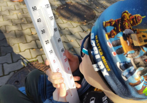 Chłopiec odczytuje temperaturę z nagrzanego termometru.