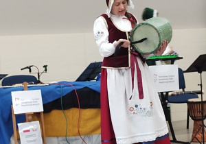 Aktorka prezentuje kaszubski instrument muzyczny "Burczybas".