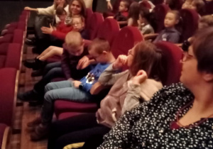 Dzieci siedzą na widowni w oczekiwaniu na przedstawienie.