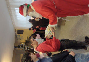 Mikołaj wręcza uczniom paczki świąteczne.