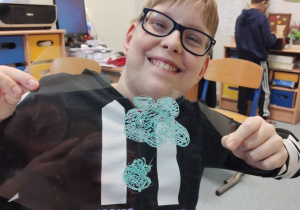 Chłopiec prezentuje kwiatek i grzybek wykonane długopisem 3D.