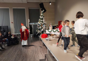 Uczniowie tańczą na scenie pod czujnym okiem św. Mikołaja.