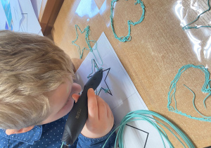 Chłopiec rysuje gwiazdkę długopisem 3D.