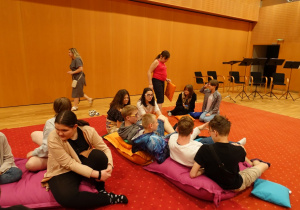 Uczniowie siedzący na poduchach w sali kameralnej.