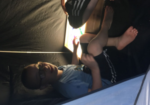 Chłopiec siedzi we wnętrzu namiotu.