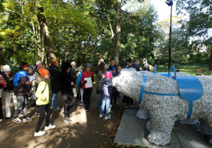 Uczniowie stoją obok pomnika niedźwiedzia.