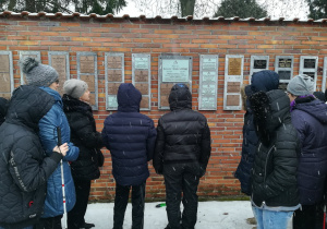 Uczniowie przed tablicą pamiątkową Patrona na Powązkach