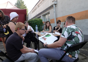 Uczniowie siedzą wokół stołu i słuchają legend o Łodzi.