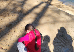 Dziewczynka kuca na plaży nad stawem