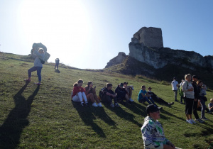 Uczniowie odpoczywają na zboczu ruin zamku Olsztyn.