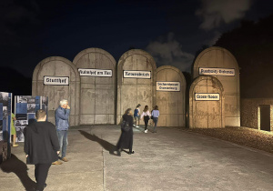 Wychowankowie przed kamiennymi płytami z nazwami miejsc obozów koncentracyjnych.