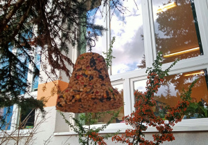 Dzwonek wykonany z różnych nasion zawieszony na drzewie.