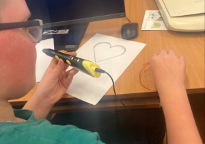 Chłopiec pracuje z długopisem 3D.
