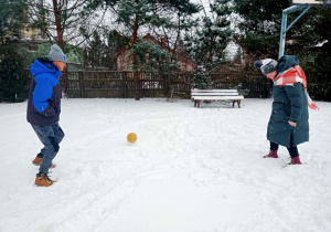 Dzieci grają w piłkę na śniegu.