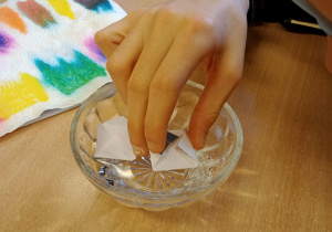Uczeń namacza papier w wodzie.