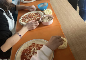 Dzieci dekorują swoje pizzce.