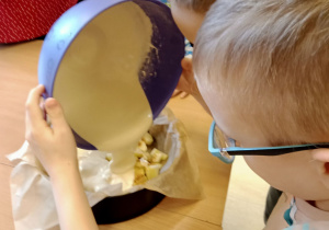 Chłopiec wlewa ciasto do formy.