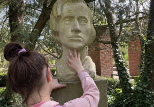 Uczennica poznaje dotykiem popiersie Fryderyka Chopina.