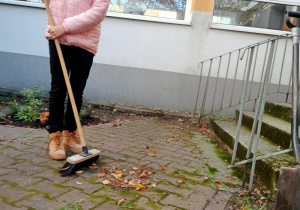 Dziewczynka zamiata liście.