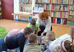 Pani bibliotekarka pokazuje dzieciom książki.