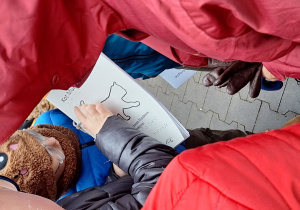 Uczniowie oglądają książeczkę o Kocie Mundku wykonaną techniką wypukłą.