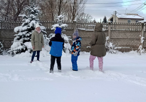 Uczniowie stoją w śniegu, w tle ośnieżona choinka.