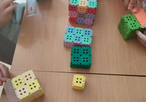 Chłopcy mierzą krawędzie wykonanych z klocków brył geometrycznych.