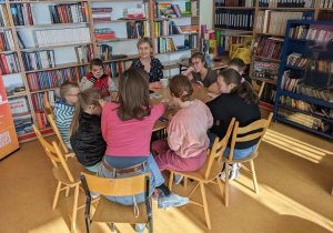 Uczniowie siedzą przy stole, przed nimi rozłożone karty.