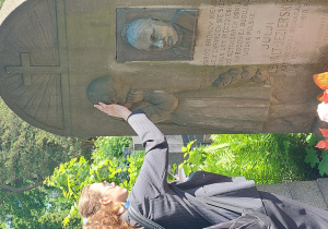 Uczennica dłońmi analizuje wypukłości zdobień na pomniku.