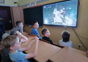 Uczniowie przed monitorem obserwują transmisję ze startu.