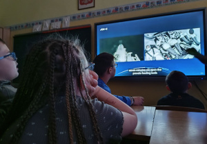 Uczniowie przed monitorem obserwują transmisję ze startu.