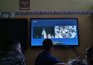 Uczniowie przed monitorem obserwują transmisję ze startu.