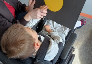 Dziewczynka dotyka dłonią namalowaną na kartce dużą kropkę.