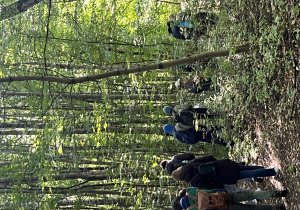 Uczniowie idący ścieżką w lesie.