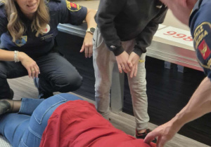 Chłopcy ćwiczą sprawdzanie czy osoba leżąca jest nieprzytomna.